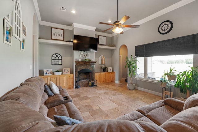 living area featuring stone tile flooring, arched walkways, visible vents, baseboards, and crown molding