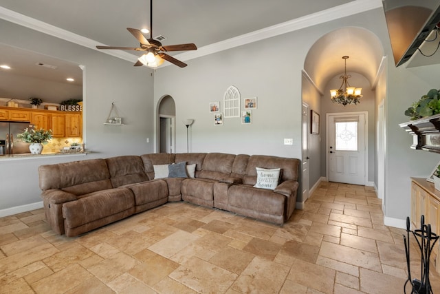 living area featuring stone tile floors, arched walkways, crown molding, baseboards, and ceiling fan with notable chandelier