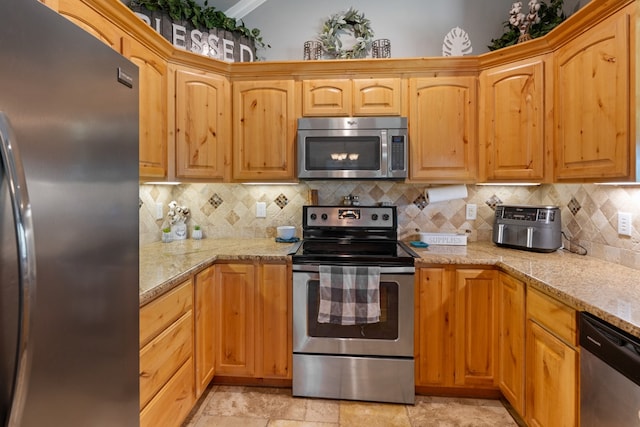 kitchen featuring light stone countertops, decorative backsplash, crown molding, and stainless steel appliances