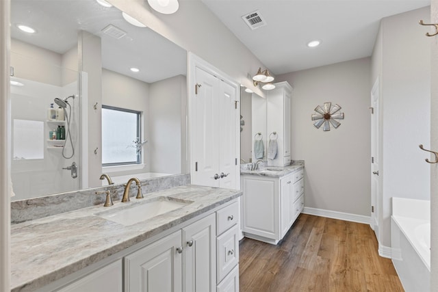 2210 County Road 1104, Cleburne, TX 76031 - full bathroom with a tub to relax in, wood finished floors, visible vents, a sink, and two vanities