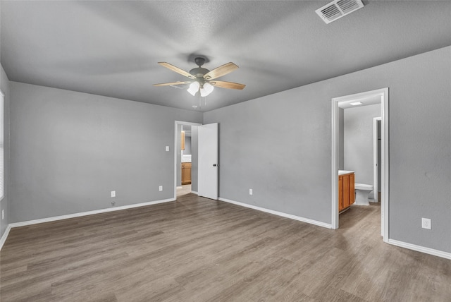 unfurnished bedroom featuring baseboards, wood finished floors, and visible vents
