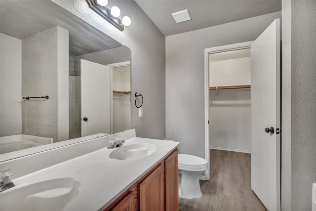 bathroom featuring a textured wall, wood finished floors, and a sink