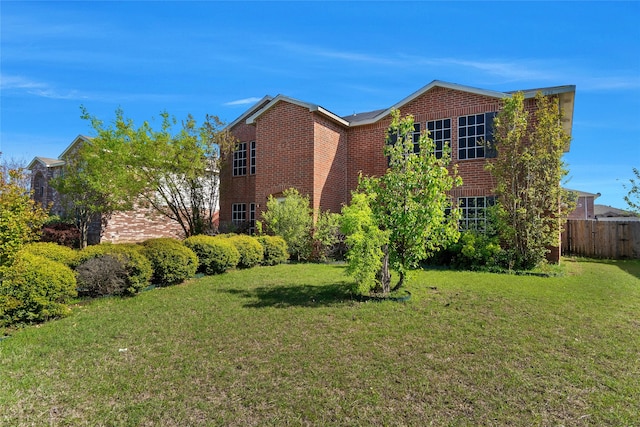 exterior space with brick siding, a lawn, and fence