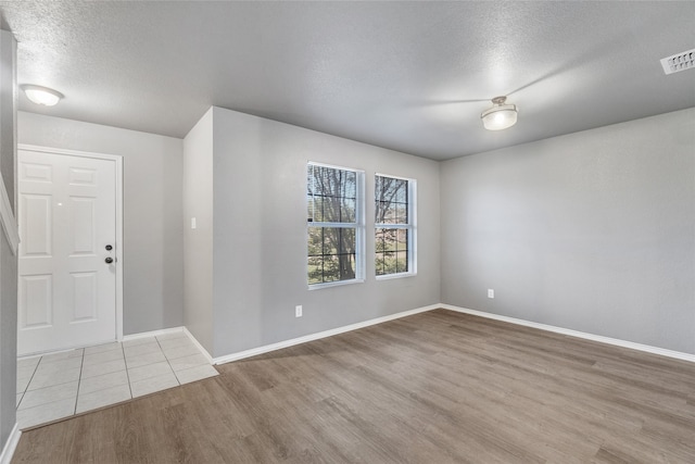 foyer featuring a textured ceiling, wood finished floors, visible vents, and baseboards