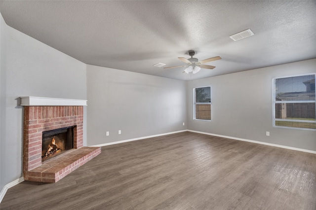 unfurnished living room with wood finished floors, visible vents, a ceiling fan, baseboards, and a textured ceiling