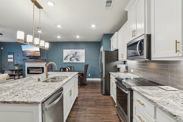 kitchen featuring a sink, a glass covered fireplace, visible vents, white cabinets, and appliances with stainless steel finishes