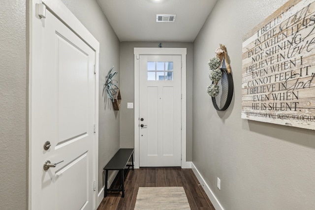 doorway featuring visible vents, dark wood-style floors, and baseboards