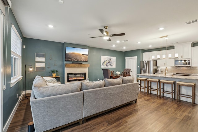 living room featuring a glass covered fireplace, visible vents, ceiling fan, and recessed lighting
