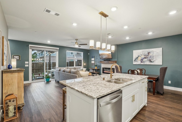 kitchen with a sink, a glass covered fireplace, dishwasher, dark wood-type flooring, and a ceiling fan