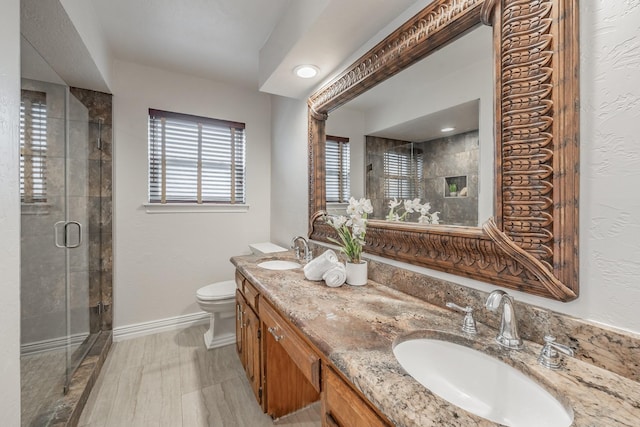 full bathroom featuring a stall shower, baseboards, a sink, and toilet