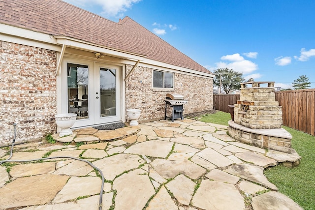 view of patio / terrace featuring french doors, a fireplace, a fenced backyard, and a grill