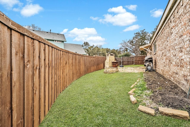 view of yard featuring a fireplace and a fenced backyard