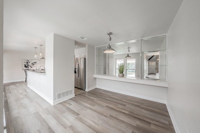 unfurnished living room featuring baseboards, wood finished floors, and visible vents