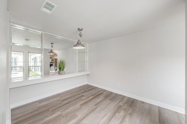 unfurnished dining area with baseboards, wood finished floors, visible vents, and a fireplace