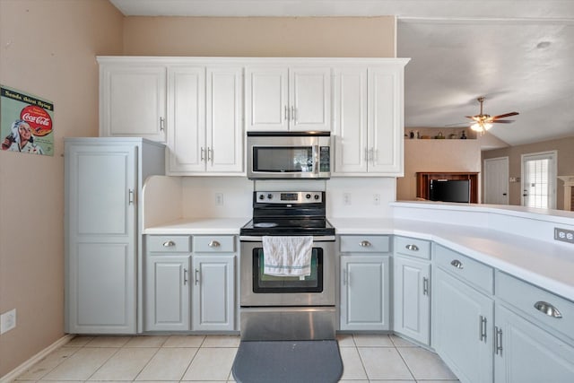 kitchen featuring light tile patterned flooring, baseboards, ceiling fan, light countertops, and appliances with stainless steel finishes