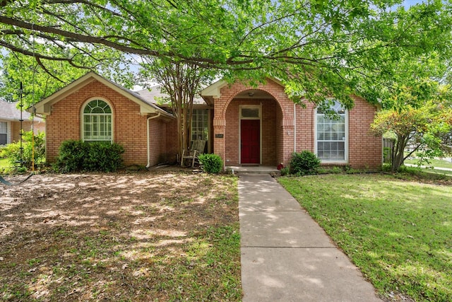 view of front facade with brick siding and a front yard