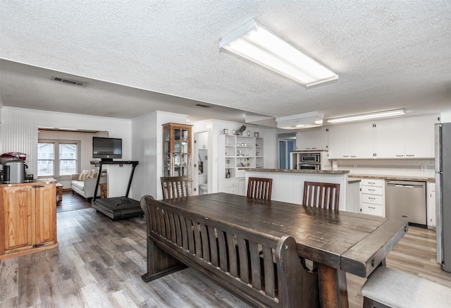 308 N Pecan St, Muenster, TX 76252 - dining space featuring light wood-type flooring, a textured ceiling, and visible vents