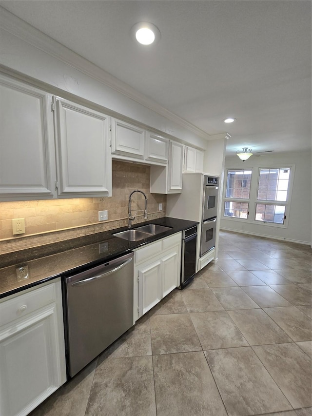 kitchen with dark countertops, ornamental molding, a sink, tasteful backsplash, and appliances with stainless steel finishes