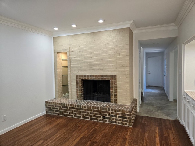unfurnished living room featuring baseboards, ornamental molding, a brick fireplace, dark wood-type flooring, and recessed lighting
