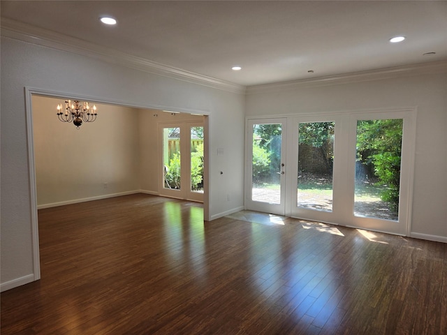 empty room with wood finished floors, crown molding, baseboards, and a notable chandelier
