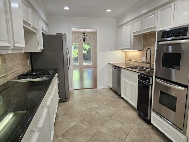 kitchen featuring a sink, an inviting chandelier, appliances with stainless steel finishes, white cabinetry, and ornamental molding