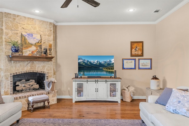living area with wood finished floors, visible vents, a ceiling fan, crown molding, and baseboards