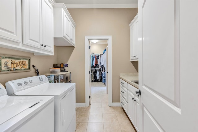 washroom featuring light tile patterned floors, crown molding, washing machine and clothes dryer, baseboards, and cabinet space