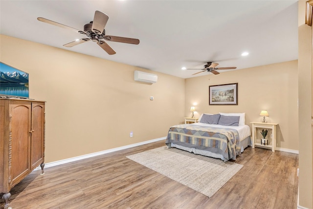 bedroom featuring light wood finished floors, baseboards, an AC wall unit, and recessed lighting