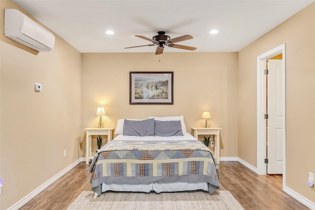 bedroom with baseboards, wood finished floors, an AC wall unit, and recessed lighting