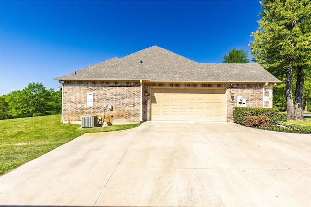 view of side of property with a shingled roof, central air condition unit, concrete driveway, a lawn, and a garage
