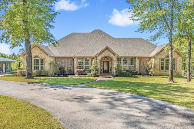 view of front facade with stone siding and a front lawn