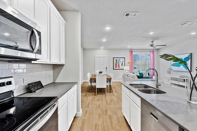 kitchen featuring tasteful backsplash, a sink, stainless steel appliances, white cabinets, and visible vents
