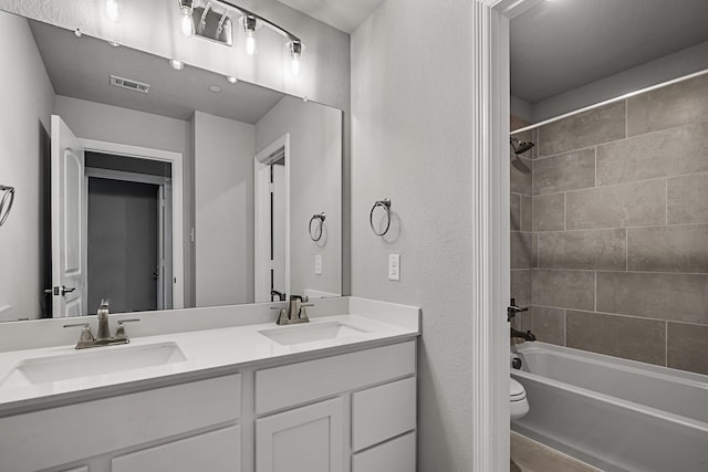 full bath with toilet, visible vents, a sink, and double vanity