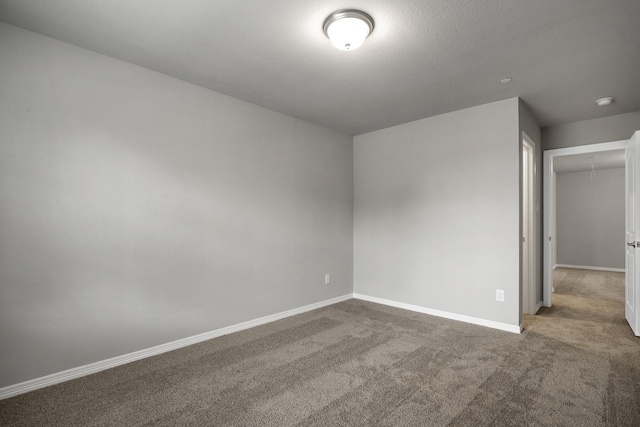 carpeted spare room with attic access and baseboards