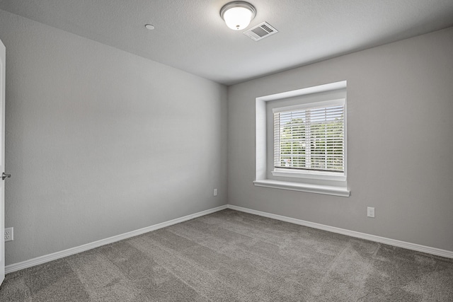 spare room featuring carpet floors, visible vents, and baseboards