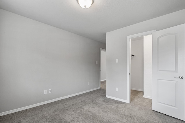 unfurnished bedroom with a walk in closet, baseboards, carpet flooring, and a closet