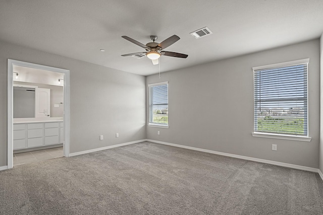 unfurnished bedroom with visible vents, a ceiling fan, light carpet, connected bathroom, and baseboards