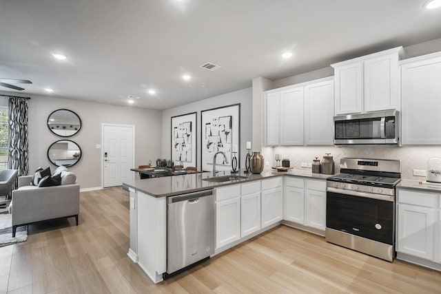 kitchen with a sink, open floor plan, light wood-style floors, stainless steel appliances, and visible vents