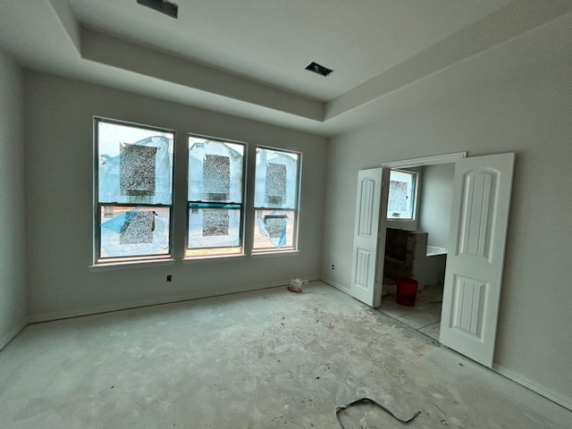 unfurnished bedroom with baseboards and a tray ceiling