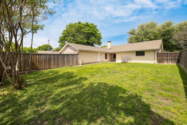 back of property featuring a chimney, a yard, cooling unit, and a fenced backyard