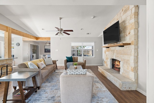 living room with lofted ceiling, wood finished floors, a stone fireplace, a ceiling fan, and washer / clothes dryer
