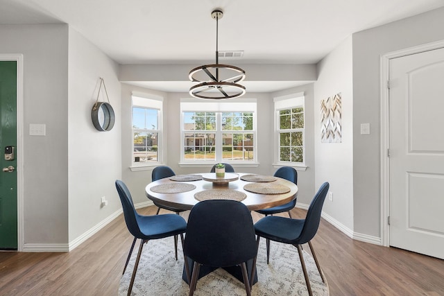 dining space with baseboards, wood finished floors, and plenty of natural light