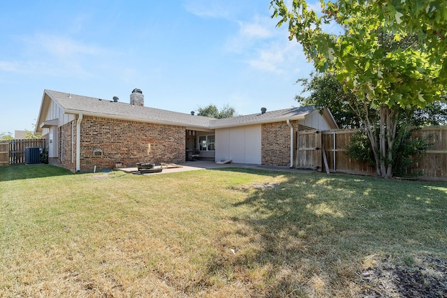 back of house with a chimney, a gate, a fenced backyard, central air condition unit, and brick siding