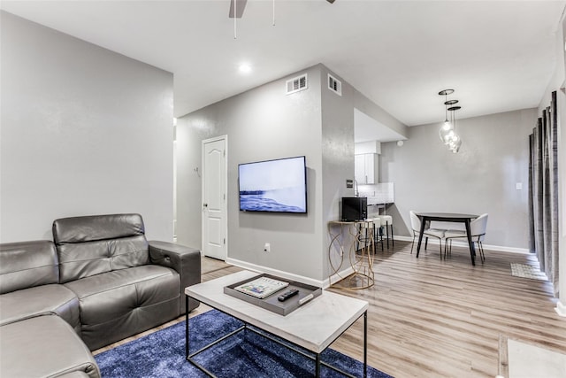 living area with light wood finished floors, baseboards, a ceiling fan, and visible vents