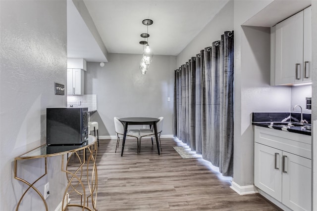 dining space with baseboards, a textured wall, and light wood-type flooring