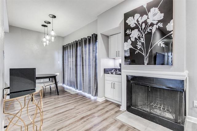 dining room with a fireplace with flush hearth, baseboards, and light wood finished floors