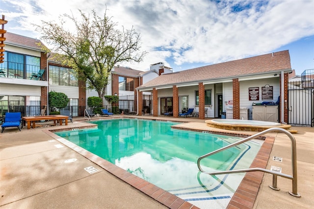 community pool with a community hot tub, a patio, and fence
