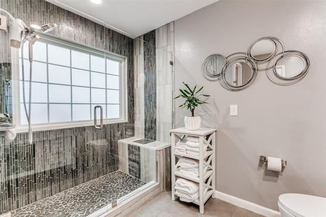 full bath featuring baseboards, tile patterned floors, a stall shower, and toilet