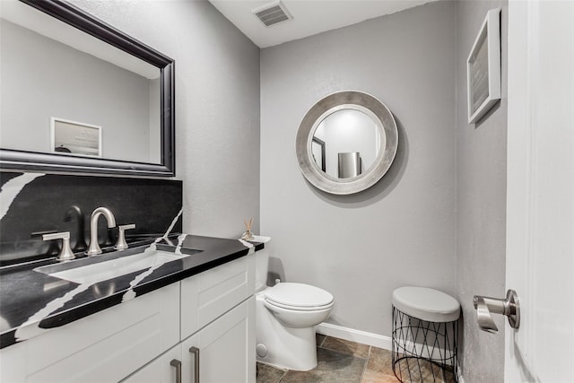bathroom featuring visible vents, toilet, baseboards, and vanity