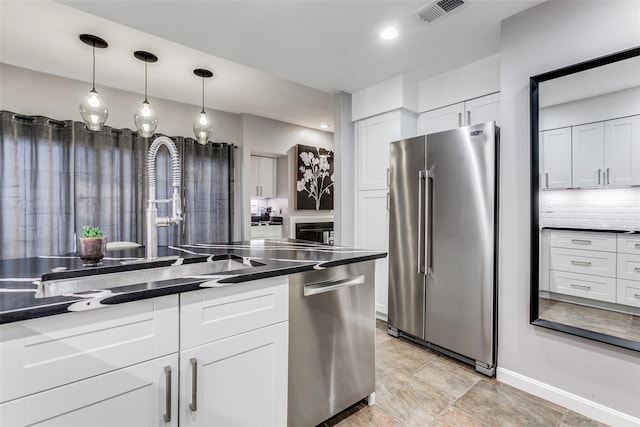 kitchen with dark countertops, stainless steel appliances, baseboards, white cabinetry, and visible vents